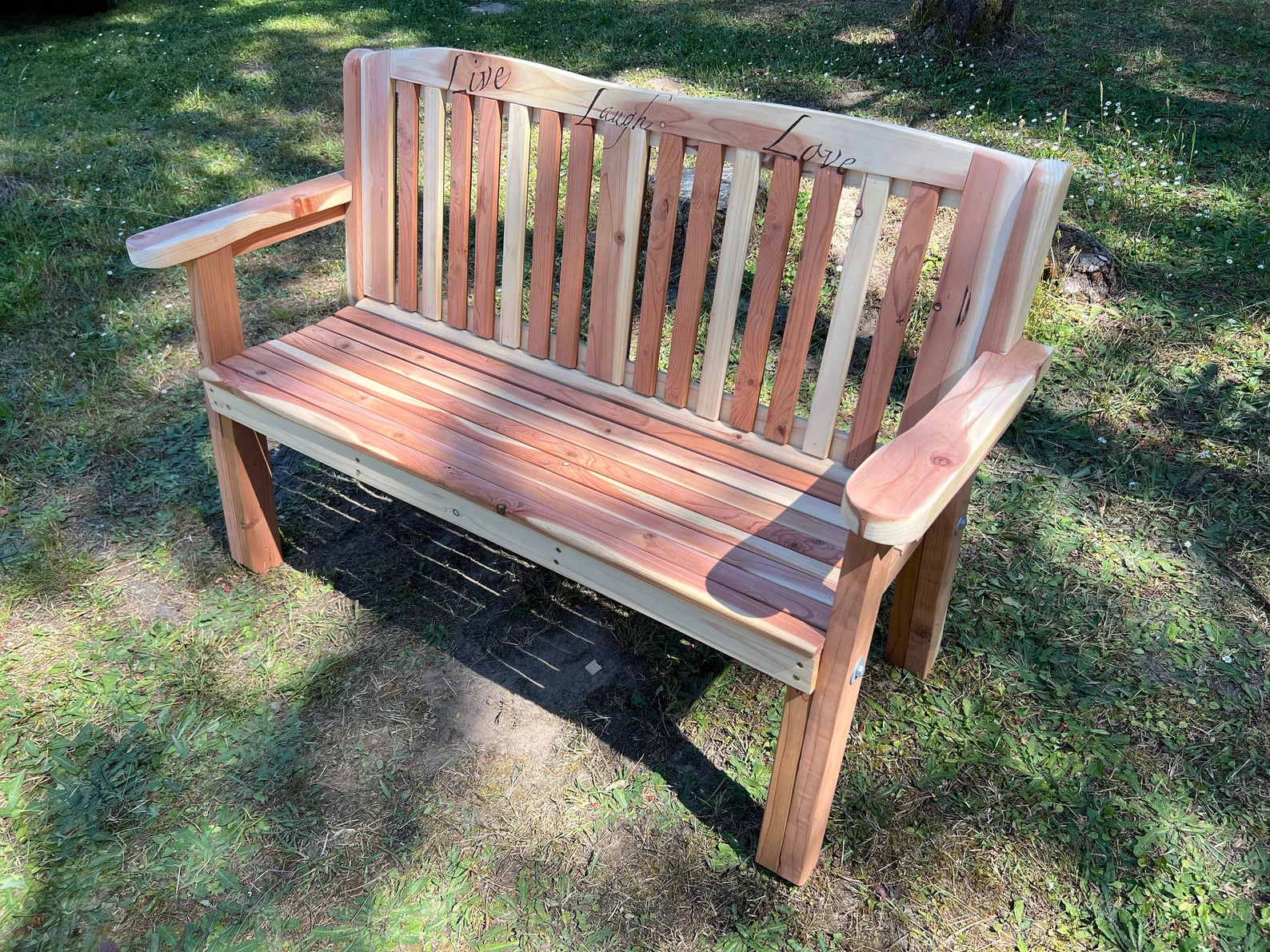 Finished outdoor garden bench built from woodworking plans – cedar and pine bench on lawn